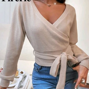 Beige omlottopp - Beige omlottopp med knytband i midjan från shein. Kommer inte till användning och säljer därför!! Använd fåtal gånger och inga defekter.💕