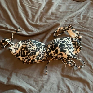 Leopardmönstrad bikiniöverdel - Snygg bikiniöverdel med leopardmönster och knytband. Perfekt för en dag på stranden eller vid poolen. Den har en klassisk trekantsform och justerbara band för bästa passform.