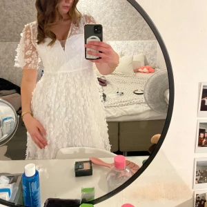 Vit blommig klänning med spetsdetaljer - Charmig vit klänning med blommigt mönster och spetsdetaljer. Den har en v-ringad design och korta ärmar i genomskinligt material. Perfekt för studenten eller midsommar!! 💕 Klänningen är från bubbelroom och är i storlek 38. Sälj pga har hittat en annan och går ej att skicka tillbaka! Ej använd bara testad!! Skriv för mer info eller bilder, pris går att diskutera!! 💕🫶nypris 999kr 