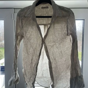 Beige skjorta från Gina Tricot - Säljer en stilren beige skjorta från Gina Tricot i linne. Skjortan har långa ärmar och knappar framtill. Perfekt för en avslappnad och chic look.