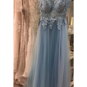 Ljusblå långklänning med spetsdetaljer - Elegant ljusblå långklänning med vacker spets upptill och en luftig kjol i tyll. Klänningen har en djup v-ringning och är ärmlös, perfekt för speciella tillfällen. Passar perfekt till bal💕 Aldrig använd! Nypris 3000kr