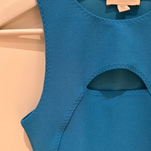 Blå ärmlös topp med cut-out - Blå ärmlös topp med en cut-out detalj framtill. Från H&M.