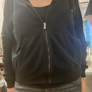 Svart hoodie från Nike - Säljer en svart hoodie från Nike med dragkedja och huva. Den har en klassisk design med Nike-loggan på bröstet. Perfekt för en avslappnad stil.