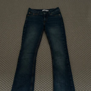 Mörkblå jeans med bootcut - Snygga mörkblå jeans med bootcut och klassisk femficksdesign. Jeansen har en diskret tvätt och är perfekta för en avslappnad stil. De har en knapp- och dragkedjestängning framtill.