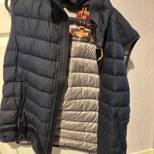 Blå dunväst från Parajumpers - Säljer en blå dunväst från Parajumpers i modellen Super Lightweight. Västen har quiltad design, dragkedja och detaljer i grått på insidan. Perfekt för lager-på-lager och har en sportig look. Köpt för 4500kr. Säljes för 2200kr. Storlek M men passar som S