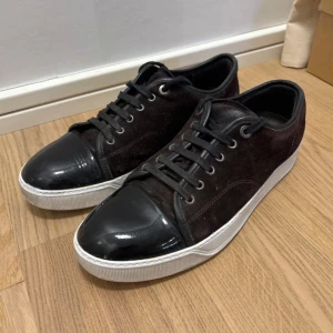 Lanvin skor - Säljer ett par svarta sneakers från Lanvin med ovandel i mocka. Skorna har vita, platta sulor och klassisk snörning. Perfekta för dig som gillar stilrena och exklusiva sneakers. PRIS KAN DISKUTERAS 