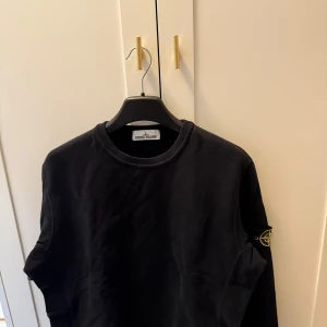 Svart sweatshirt från Stone Island - Säljer en svart sweatshirt från Stone Island med rund hals och logotyp-patch på ärmen. 