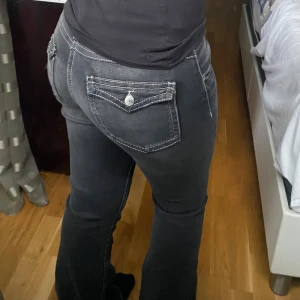 Svarta bootcut jeans  - Svarta bootcut jeans från Gina Tricot, byxorna har snygga bakfickor med lock och knapp🤩. Byxorna har knappt använts och har inga defekter. Strl står 170 men jag har sytt om dem till mindre längdstorlek. Midjemått: 76cm runtom, Innerben:76cm, Längden: 100cm. Skriv via dm vid funderingar 💬💗 