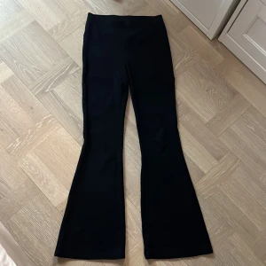 Svarta utsvängda byxor från Lindex - Svarta byxor från Lindex med utsvängda ben. Byxorna har en hög midja och är sydda i ett stretchigt material som ger en bekväm passform. Perfekta för dig som gillar en trendig och stilren look.