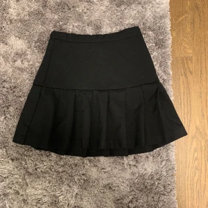 Svart kjol med volang från H&M - Säljer en svart kjol från H&M med volangdetalj nedtill. Kjolen har en klassisk, enkel design och är perfekt för dig som gillar stilrena plagg. Passar till många olika looks och är lätt att matcha.