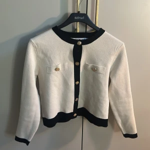 Vit och svart kofta från Design by Amor - Säljer en stilren vit kofta med svarta detaljer från Design by Amor. Så snygg för middagar!! nyköpt och använd få gånger!