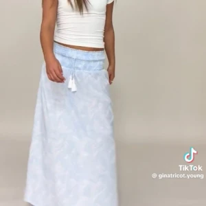 Ljusblå långkjol med smock från Gina Tricot - Supersöt ljusblå långkjol från Gina Tricot med smock i midjan och knytband med tofsar. Säljer för att den är för liten, använd max två gånger. Superfin nu till sommaren!☀️ hör av er om ni har någon fråga❤️