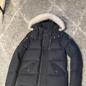 Svart dunjacka med pälskant från Moose Knuckles - Den är använd 10 gånger ungefär. använd som skidjacka så den har inga skråmor eller någonting, kanske någon enstaka fläck som naturligtvis går att få bort med lite vatten