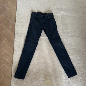 Mörkblå Replay Anbass jeans - Säljer ett par mörkblå Replay Anbass jeans i slim fit. Klassisk femficksmodell med dragkedja och snygga detaljer. Perfekta för dig som gillar en smalare passform och stilren look. Jeansen är som nya och köpta för 1600kr på replays egna hemsida