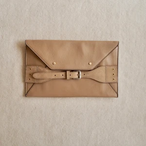 Beige kuvertväska med bältedetalj - Stilren beige kuvertväska i skinn med snygg bältedetalj och metallspänne på framsidan. 