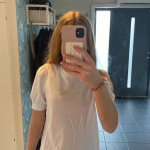 Vit topp med puffärm från Aware by Vero Moda - Säljer en vit topp från Aware by Vero Moda med puffärmar och rund halsringning. T-shirten är i mjuk bomull och har en enkel, stilren design som passar perfekt som basplagg 