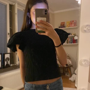 Svart topp med volangärmar - Säljer en söt  svart topp med korta volangärmar. Har deo fläck men det tvättar jag. Inte använd mycket. Liten storlek men passar mig så är 13!💕