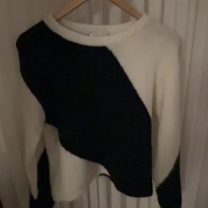 Vit och svart stickad tröja - Säljer en stickad tröja i vitt med stora svarta partier. Tröjan har rund halsringning och långa ärmar. Perfekt för dig som gillar en unik och stilren look. Använd bara en gång 💘