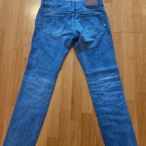 Blå slim fit jeans från BOSS  - Säljer ett par klassiska blå jeans från BOSS, modell Delaware Slim Fit. Jeansen har fem fickor, raka ben. Perfekta för en stilren och modern look. W32 L32