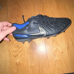 Nike Tiempo fotbollsskor i svart och blå - Säljer ett par Nike Tiempo fotbollsskor storlek 41. Nysick har bara använt de ett par några gånger. Anledningen för varför jag säljer de är för de är för små på mig.