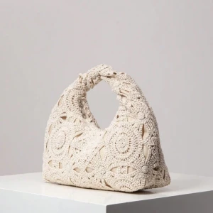 Beige virkad axelväska - Superfin beige axelväska med virkat mönster och rundad form. Väskan har ett handtag upptill och är perfekt för att addera en bohemisk touch till din outfit. Den är lätt och smidig att bära med sig och passar till många olika stilar.