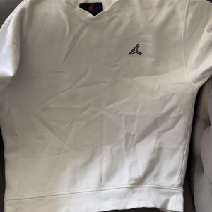 Vit sweatshirt från Jordan - Säljer en stilren vit sweatshirt från Jordan med det klassiska broderade Jumpman-loggan på bröstet. Tröjan har rund halsringning och långa ärmar. Perfekt för en sportig och avslappnad look.