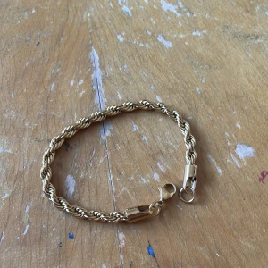 Guldfärgat cordell armband  - Säljer ett snyggt guldfärgat armband med tvinnad kedja och karbinlås det är 17cm långt. Perfekt accessoar för att lyfta din stil med en klassisk touch. Passar till många olika outfits och är lätt att bära. Aldrig använt jag köpte det precis men det var för litet.