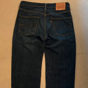 Levis 502 jeans - Snygga Levis 502 jeans i en klassisk blå färg. De har en normal passform och är tillverkade i slitstarkt denim. Perfekta för en avslappnad stil med fem fickor och knappgylf.