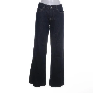 Mörkblå jeans med vida ben - Snygga svarta jeans med låg midja och vida ben. Perfekta för en trendig look. Klassisk femficksdesign och knappgylf. Från Gina Tricot 