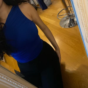 Blå oneshoulder topp från Bik Bok - Säljer en snygg blå oneshoulder topp från Bik Bok. Toppen har en tight passform och är perfekt för en kväll ute. Silkesmaterial. Aldrig använt.