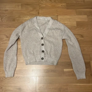Beige stickad kofta från H&M - Säljer en mysig beige stickad kofta från H&M. Den har långa ärmar och knäpps med fem knappar framtill. Den har använts 1 eller 2 gånger bara.