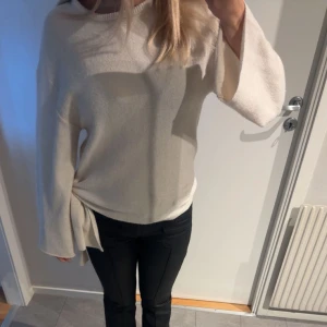 Beige tröja med knytband - Säljer en stilren beige tröja med långa ärmar och ett snyggt knytband i sidan. Perfekt för en avslappnad look. Tröjan har en lös passform och är tillverkad i ett mjukt material.