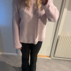 Ljusrosa stickad tröja - Mysig ljusrosa stickad tröja med långärmad design. Perfekt för kyligare dagar med sin bekväma passform och ribbade muddar vid ärmslut och nederkant.