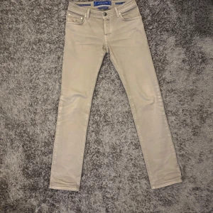 Beige Jeans från Jacob Cohën - Snygga beigea jeans från Jacob Cohën i en stilren design. Byxorna har en klassisk femficksmodell med knappgylf och är tillverkade i ett mjukt bomullsmaterial. Perfekta för en stilren look.