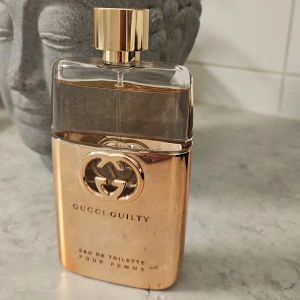 Gucci Guilty Eau de Toilette Pour Femme - Elegant parfymflaska från Gucci Guilty i en lyxig guldton. Flaskan har en stilren design med det ikoniska Gucci-emblemet i mitten. Perfekt för den som vill ha en sofistikerad doftupplevelse. 90 ml oanvänd, äkta!