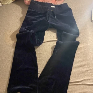 Låg midjade marin blåa juciy couture bootcut byxor - Säljer ett par marinblå juicy bootcut mjukisbyxor med snörning i midjan. Byxorna har en bekväm passform och är perfekta för en avslappnad stil. De är tillverkade i ett mjukt material som känns skönt mot huden. Super snygga och sitter perfekt inga skador. Köpte dom för 1000kr säljer dom billigare 