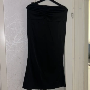 satin kjol - Snygg svart kjol med rynkdetalj vid bysten. Perfekt för en elegant kvällslook. Kjol har en enkel och stilren design som gör den lätt att matcha med accessoarer.