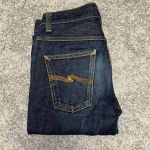 Nudie Jeans Grim Tim - Snygga mörkblå jeans från Nudie Jeans. Jeansen har en smal passform och är tillverkade i högkvalitativt denim. PRISET ÄR EJ HUGGET I STEN! Liten rivning vid botten