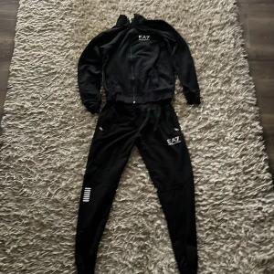 Tracksuit från Emporio Armani EA7 - Säljer en svart tracksuit från EA7, zip-uppen är lite mindre än byxorna. Den är storlek S men sitter lite tajtare. Vet inte vad materialet är men kan vara en polyester och bomull blandning. Vill du köpa enskild plagg så skriv.