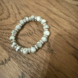 Armband med marmorerade pärlor och strass - Armband med vita marmorerade pärlor och glittrande strassdetaljer mellan varje pärla. Köpt utomlands. Knappt använd.
