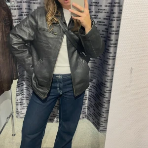 Svart skinnjacka - Säljer en klassisk svart skinnjacka som är köpt second hand på Humana. Jackan har dragkedja framtill och två fickor med dragkedja på bröstet. Äkta skinn i vintage skick, står ingen storlek i men passar mig som är 167 cm
