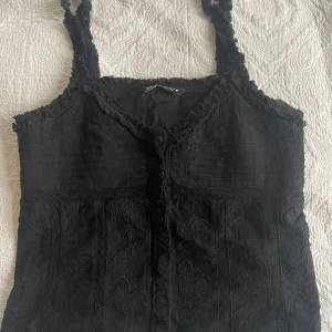 Svart spetslinne - Säljer ett svart linne med spetsdetaljer och smala axelband. Superfin till sommaren💗