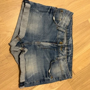 Blå jeansshorts från Diesel - Snygga blå jeansshorts från Diesel med klassisk femficksdesign och uppvikta ben. Perfekta för en avslappnad stil. De har en bekväm passform och är tillverkade i slitstarkt denim.