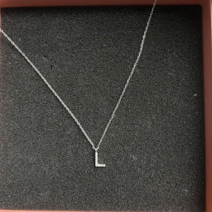 Silverhalsband med bokstav L från Edblad - Elegant silverhalsband från Edblad med en liten bokstavsberlock 'L'. Perfekt för att ge en personlig touch till din stil. Kedjan är tunn och smidig, vilket gör den lätt att bära varje dag. SKRIV INNAN KÖP❤️ pris kan diskuteras ❤️❤️