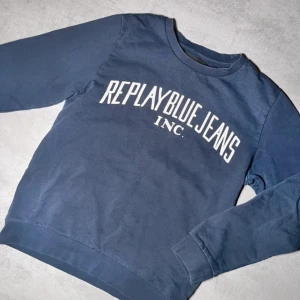 Blå sweatshirt från Replay - Säljer en blå sweatshirt från Replay med tryck 'Replay Blue Jeans Inc.' på framsidan. Tröjan har långa ärmar och en rund halsringning. Perfekt för en avslappnad stil.