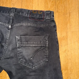 Gråa Dondup jeansbyxor - Snygga svarta jeansbyxor med klassisk femficksdesign från Dondup. Byxorna har en knapp och knapp dragkedja framtill samt bälteshällor. Perfekta för en stilren look.