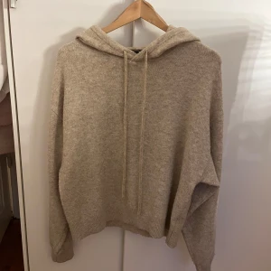 Beige stickad hoodie från Lindex - Mysig beige stickad hoodie från Lindex i storlek XS. Tröjan har huva med dragsko och ribbade muddar vid ärmslut och nederkant. Perfekt för lager-på-lager och chill dagar.