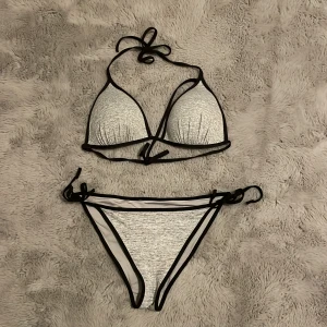 Grå svart halter strap bikini - Fin grå svart halter strap bikini med knyte 👙 Storlek S och passar från xs-m, kupa 70-75B till 70-75C beroende på hur du vill den ska sitta. Då den har knyte så är båda delarna rätt justerbara! Använt den runt 5-8 gånger. Den har en liten defekt på bild 3 där tråden/ludd syns lite men det är inget man tänker på. ❌Visar inte med den på❌ Säljer den för det inte är min stil längre!