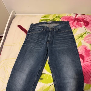 Blå jeans från Dressmann Athletic Fit - Säljer ett par klassiska blå jeans från Dressmann i modellen Athletic Fit. Jeansen har fem fickor, normal passform och raka ben. Perfekta för dig som vill ha en enkel och stilren look till vardags.