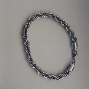 Silverfärgat tvinnat armband - Armband i silverfärg med tvinnad kedja och karbinlås. Armbandet är cirka 21 cm långt